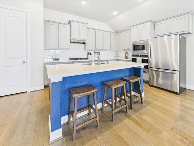 Kitchen with a sink, light wood-style flooring, under cabinet range hood, stainless steel appliances, and decorative backsplash | Image 5