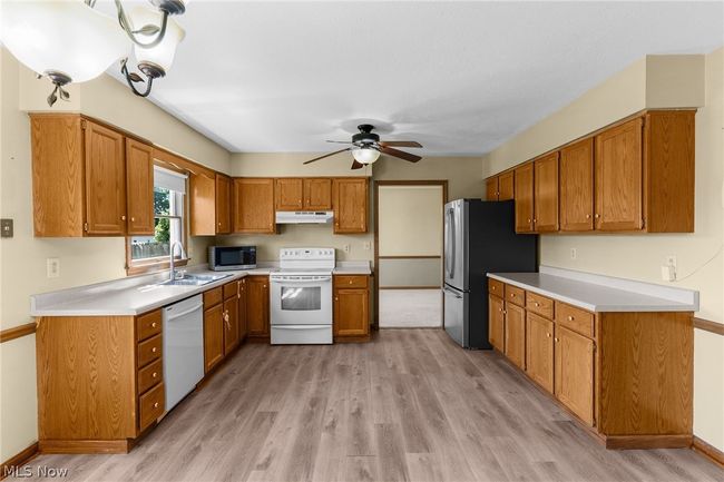 Kitchen featuring appliances with stainless steel finishes, sink, ceiling fan, and light hardwood / wood-style flooring | Image 11