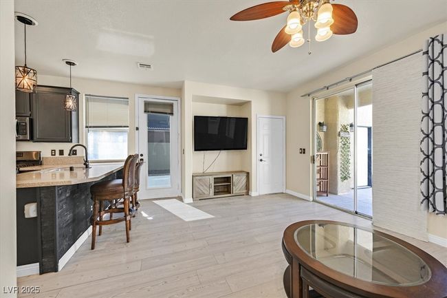 Living area with light wood-type flooring, visible vents, baseboards, and a ceiling fan | Image 11