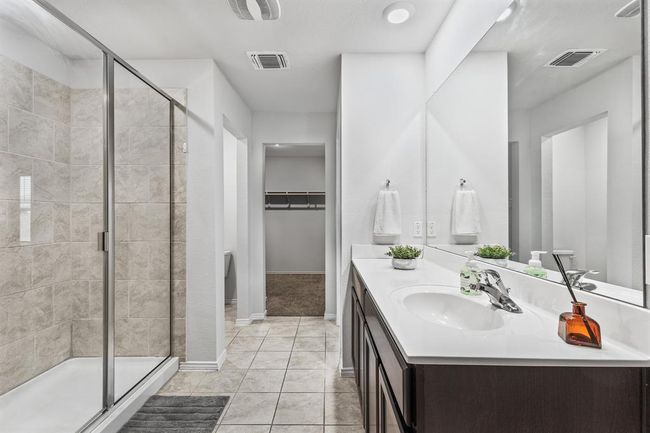 Bathroom featuring vanity, a shower stall, a spacious closet, and tile patterned flooring | Image 10