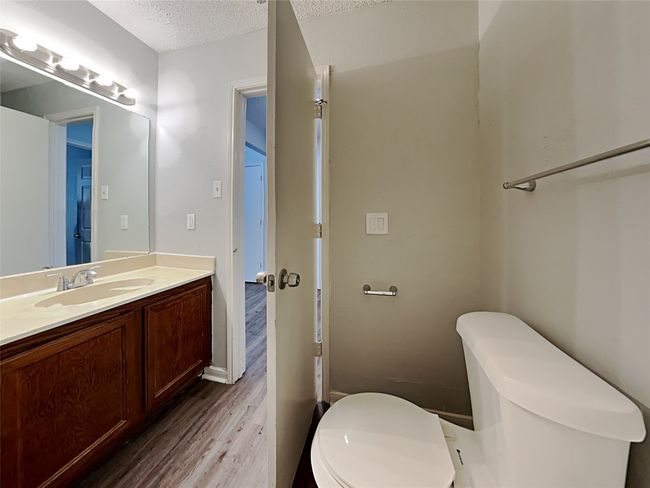Half bathroom featuring wood finished floors, a textured ceiling, and vanity | Image 14