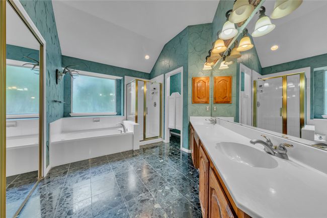 Bathroom featuring vaulted ceiling, a bath, a shower stall, double vanity, and recessed lighting | Image 15