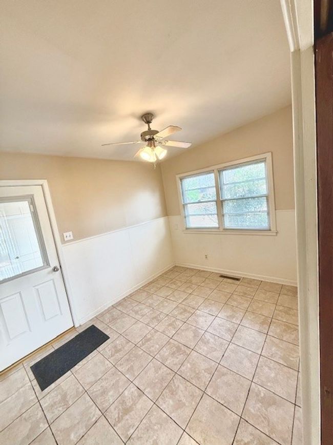 Spare room featuring a wainscoted wall, visible vents, light tile patterned floors, and a ceiling fan | Image 17