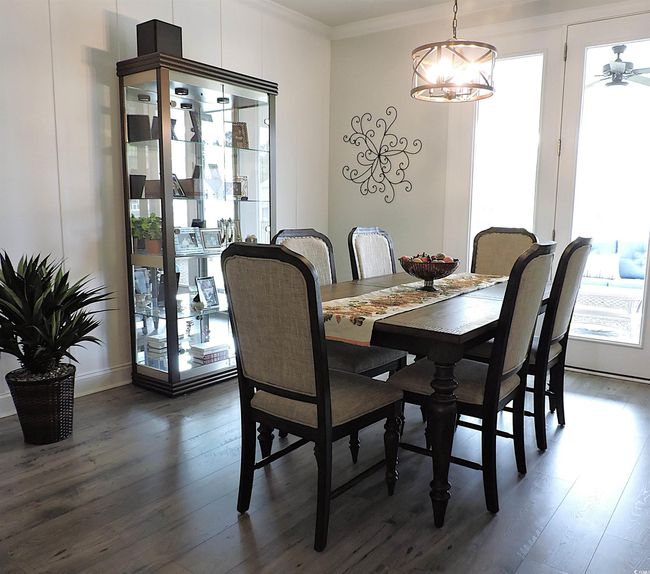 Dining space with dark wood-style flooring, ornamental molding, and a chandelier | Image 14
