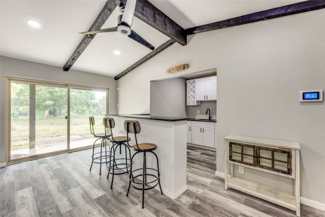 Kitchen with a kitchen breakfast bar, white cabinets, dark countertops, light wood-style floors, and a peninsula | Image 16