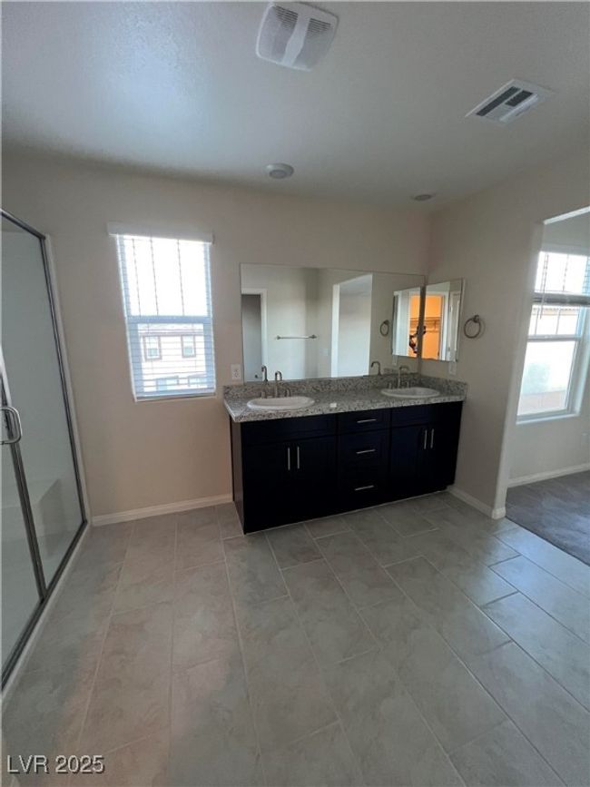 Bathroom with plenty of natural light, a stall shower, double vanity, and baseboards | Image 13