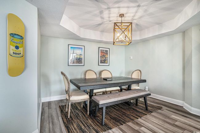 Dining area featuring a raised ceiling, dark wood-style floors, and a chandelier | Image 9