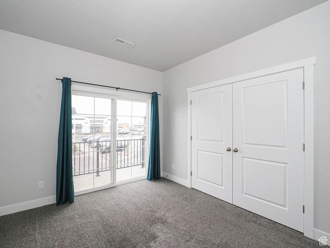 Unfurnished bedroom featuring carpet flooring, baseboards, access to outside, and visible vents | Image 26