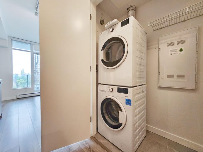 Clothes washing area featuring stacked washing machine and dryer, a baseboard heating unit, and baseboards | Image 8