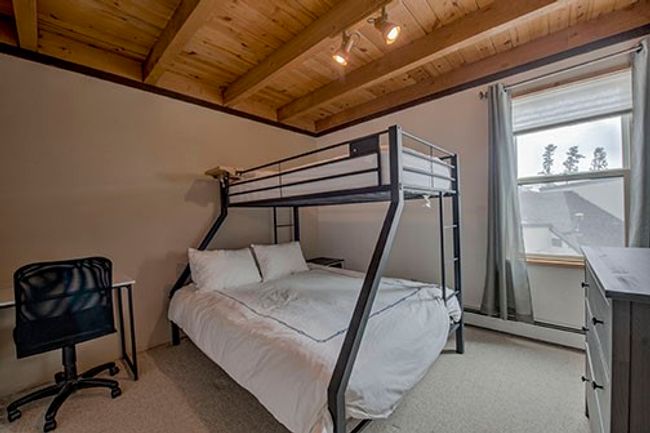 Bedroom with wood ceiling, baseboard heating, light carpet. | Image 10