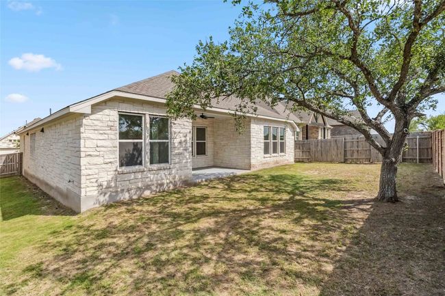 Back of property featuring a fenced backyard, a patio area, roof with shingles, and stone siding | Image 38