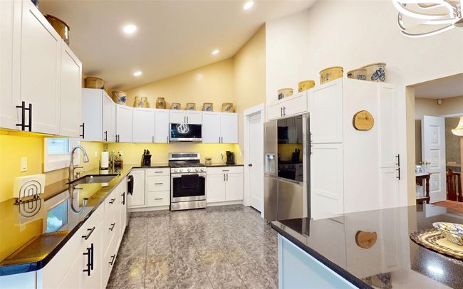 Kitchen featuring appliances with stainless steel finishes, a sink, high vaulted ceiling, white cabinets, and recessed lighting | Image 19