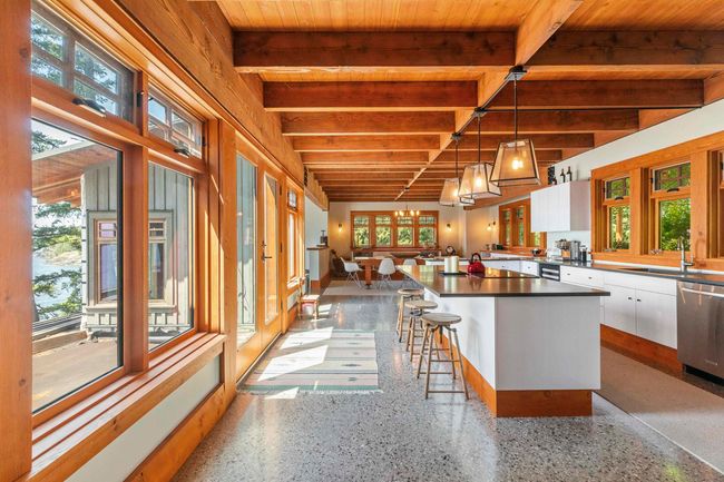Kitchen with stainless steel dishwasher, healthy amount of natural light, a sink, speckle patterned floor, and wooden ceiling with exposed beams | Image 6