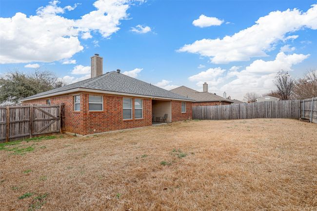 Rear view of property featuring a chimney, brick siding, a lawn, and a fenced backyard | Image 35