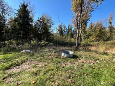 North facing photo of property with a cleared area & firepit located next to an existing garden area. | Image 1