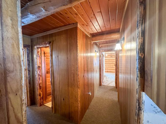 Corridor featuring beamed ceiling, wooden walls, light carpet, and wooden ceiling | Image 32