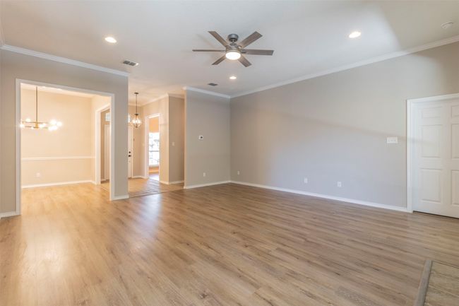 Spare room with baseboards, light wood-type flooring, visible vents, and ceiling fan with notable chandelier | Image 8
