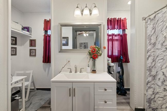 Full bath featuring wood finished floors, vanity, a textured wall, and ceiling fan | Image 12