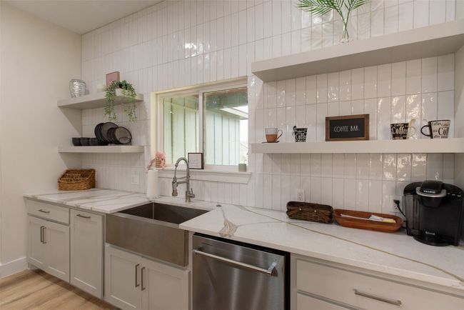 Kitchen featuring dishwasher, sink, light stone counters, backsplash, and light hardwood / wood-style floors | Image 10