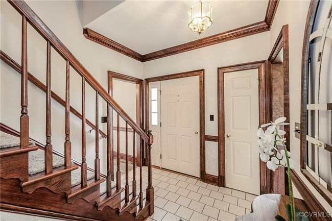 Foyer featuring stairway, a chandelier, crown molding, and light tile patterned flooring | Image 11