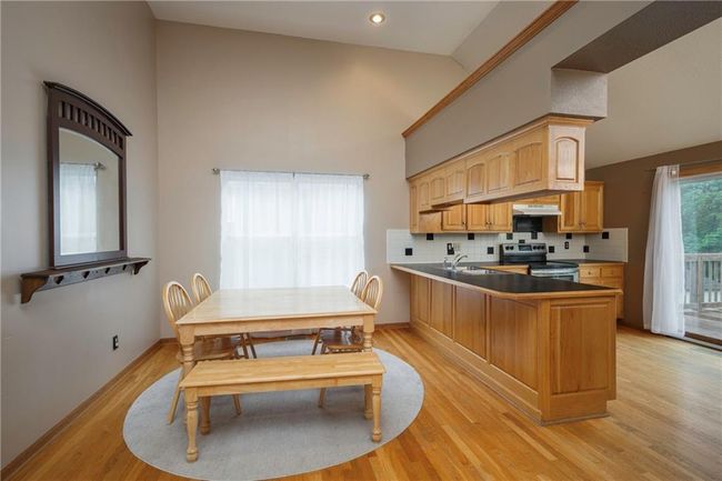 Kitchen featuring stainless steel electric range oven, under cabinet range hood, high vaulted ceiling, a sink, and light wood-type flooring | Image 11