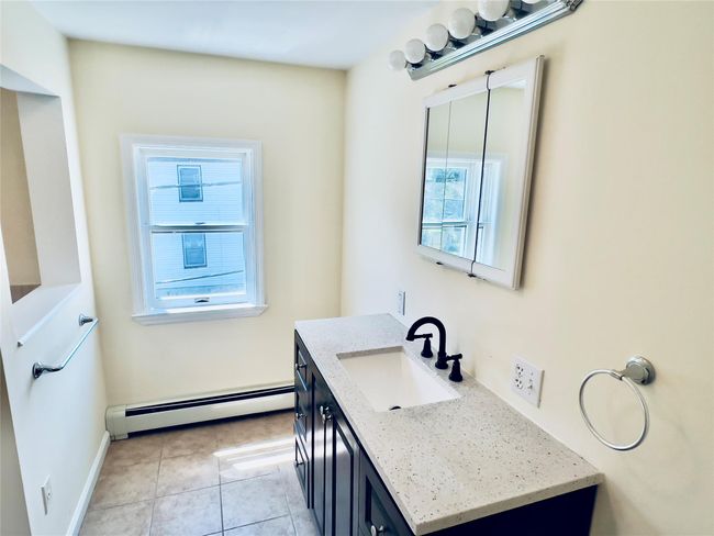 Bathroom featuring baseboard heating, vanity, and tile patterned flooring | Image 9