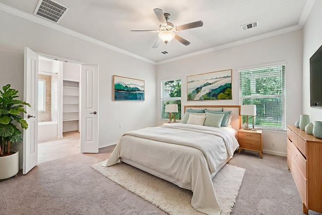 Virtually Staged Primary Bedroom featuring light colored carpet, baseboards, crown molding, ceiling fan, and a spacious closet | Image 19