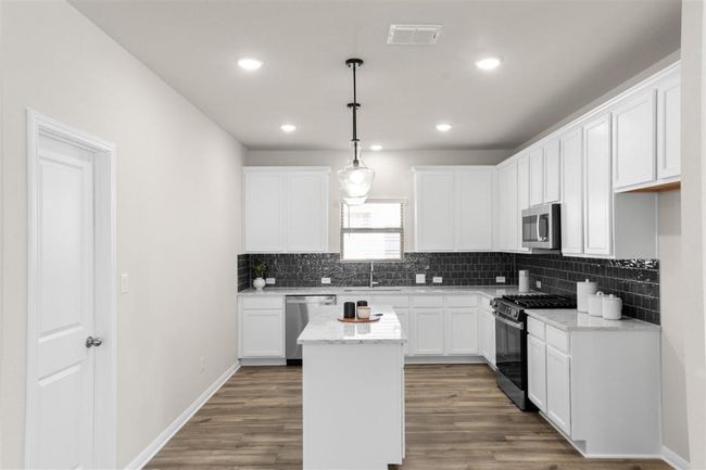 Kitchen with a center island, visible vents, wood finished floors, and appliances with stainless steel finishes | Image 15