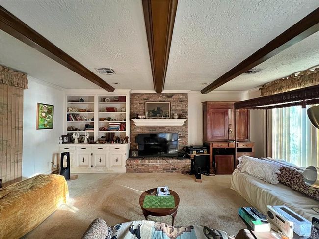 Expansive living room featuring a cozy fireplace, built-in shelves, and scenic backyard views. | Image 5