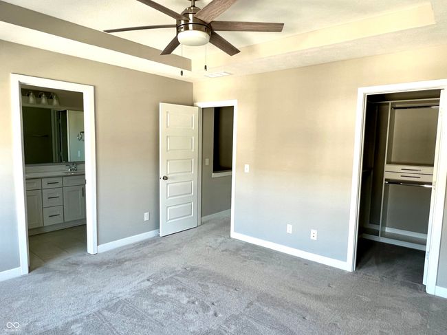 Primary bedroom with tray ceiling, custom blinds, ceiling fan & customized walk-in closet | Image 43