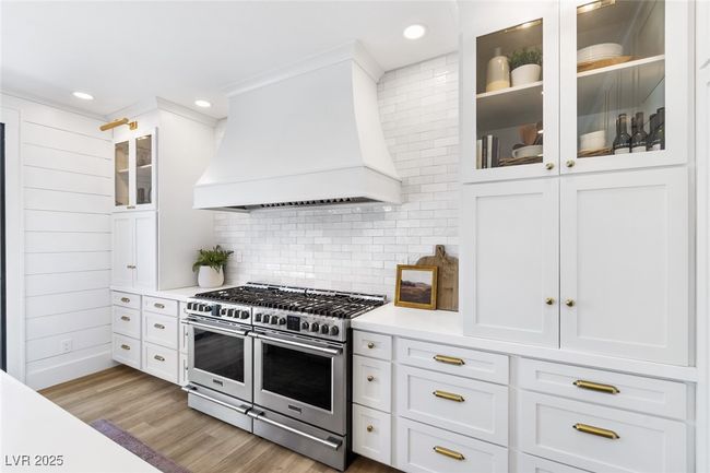 Kitchen featuring white cabinets, backsplash, custom range hood, range with two ovens, and light countertops | Image 15