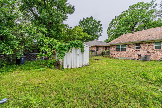 View of yard featuring central AC, an outdoor structure, a fenced backyard, and a storage shed | Image 33