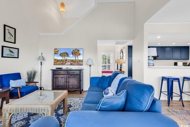 Living room with visible vents, baseboards, wood finished floors, and high vaulted ceiling | Image 15