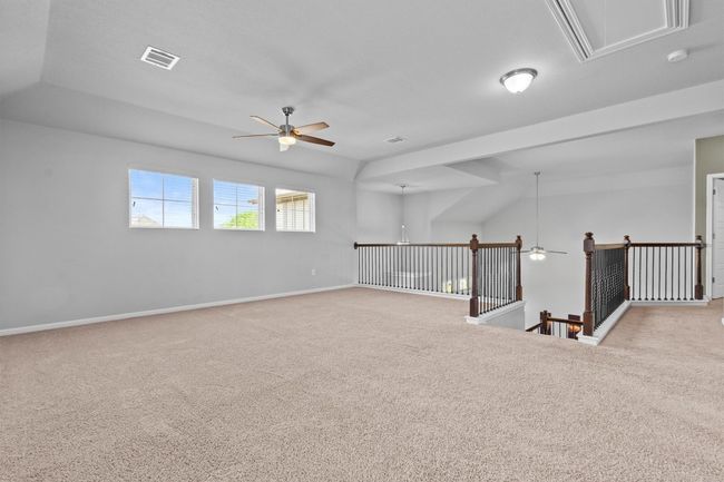 Carpeted empty room with a ceiling fan, attic access, baseboards, and a smoke detector | Image 24