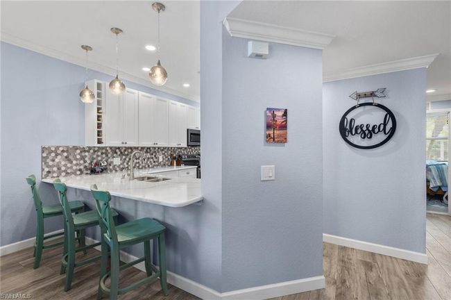 Kitchen with tasteful backsplash, sink, white cabinets, kitchen peninsula, and crown molding | Image 8