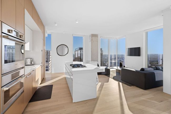 Kitchen with modern cabinets, light wood-style flooring, stainless steel appliances, and a wall of windows | Image 5