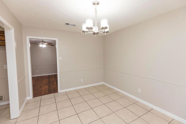 Unfurnished room featuring a chandelier, ceiling fan, and a decorative wall | Image 7