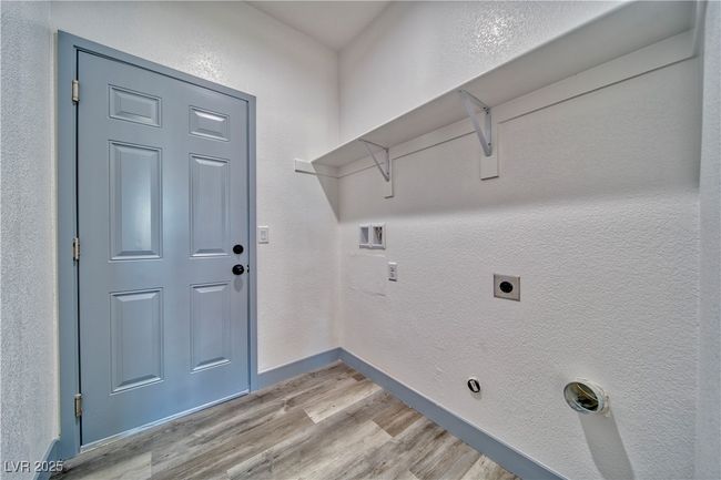 Convenient utility room with built-in shelving, offering access from both the garage and main hallway for seamless functionality. | Image 7