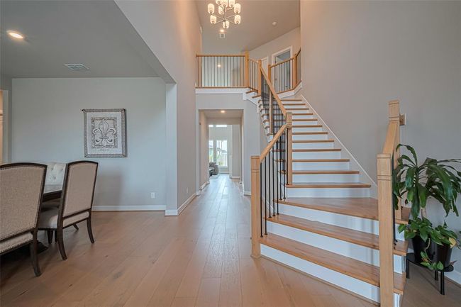 Natural light flows in from large windows, enhancing the spacious feel. The adjacent dining area has elegant seating, and a chandelier provides a warm ambiance. | Image 6