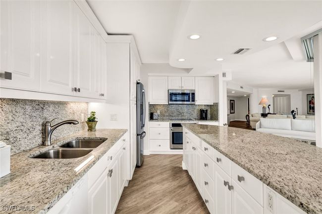 Kitchen featuring light stone counters, a sink, stainless steel appliances, light wood-style flooring, and visible vents | Image 15