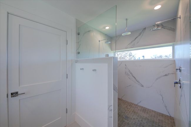 The en suite primary bathroom features an oversized walk-in shower wrapped in gorgeous calacatta marble-look tile. Relax under the rain shower head as you take in the views of downtown Austin. | Image 23