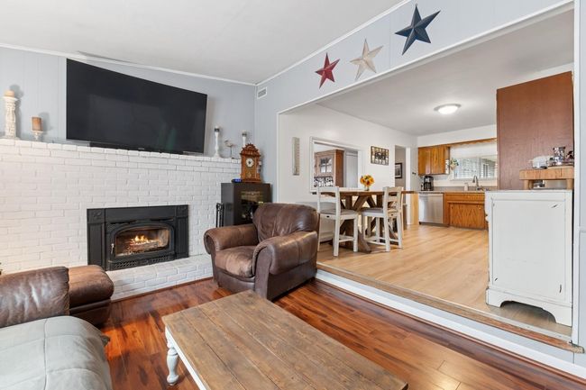 Den area featuring crown molding, light wood-style flooring, and a brick fireplace | Image 5