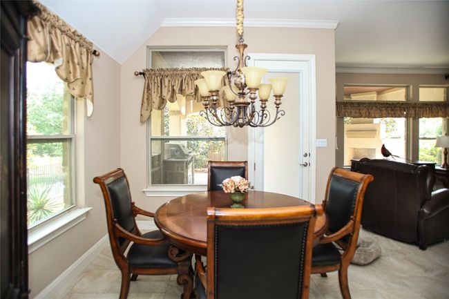 Dining area with a chandelier, plenty of natural light, baseboards, ornamental molding, and light marble finish floors | Image 6