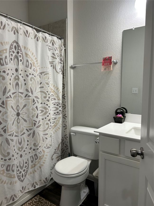 Bathroom featuring vanity, a textured wall, toilet, and a shower with shower curtain | Image 5