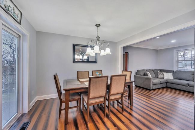Dining room with baseboards, dark wood-style floors, visible vents, and a notable chandelier | Image 8