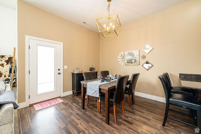 Dining area with visible vents, baseboards, dark wood-style floors, and a chandelier | Image 10