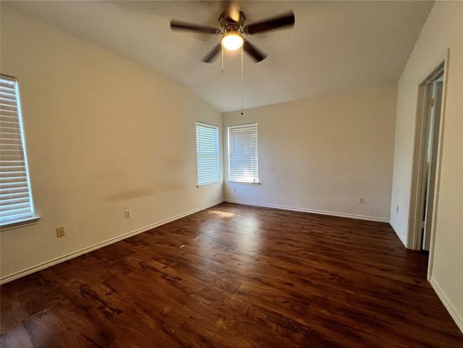 Spare room featuring vaulted ceiling, dark wood-style flooring, ceiling fan, and baseboards | Image 7