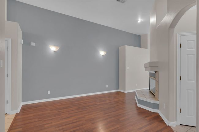 Unfurnished living room featuring arched walkways, wood finished floors, and a tiled fireplace | Image 33