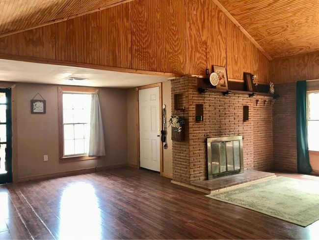 Unfurnished living room with high vaulted ceiling, a brick fireplace, wood ceiling, and a healthy amount of sunlight | Image 7