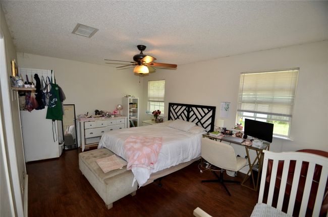 Bedroom with dark wood-style flooring, a textured ceiling, and a ceiling fan | Image 4